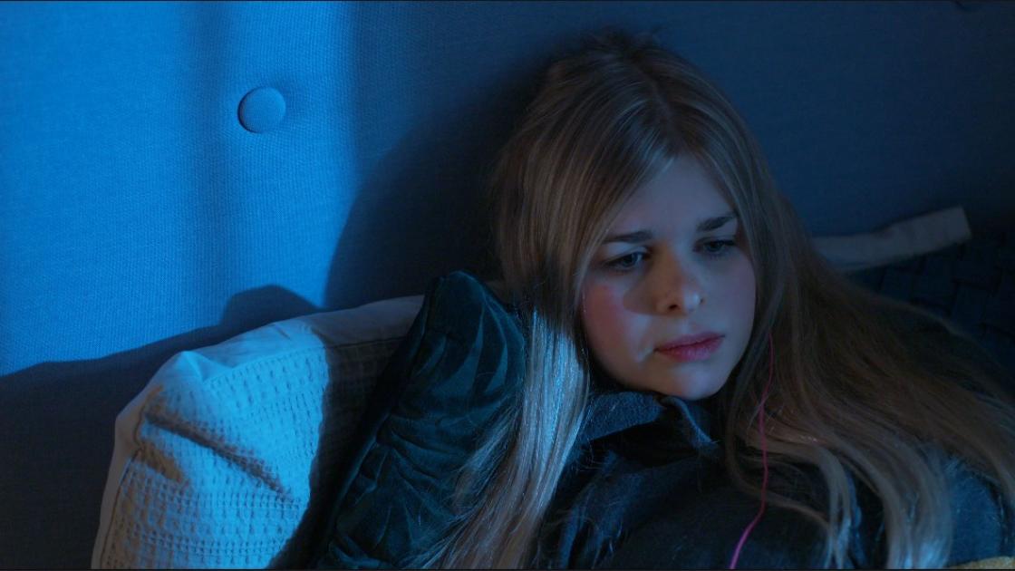 a girl sits in bed looking sad