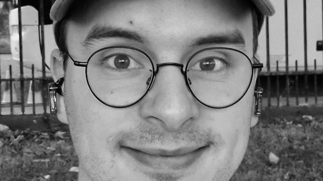 a black and white image of a man wearing glasses and a baseball cap