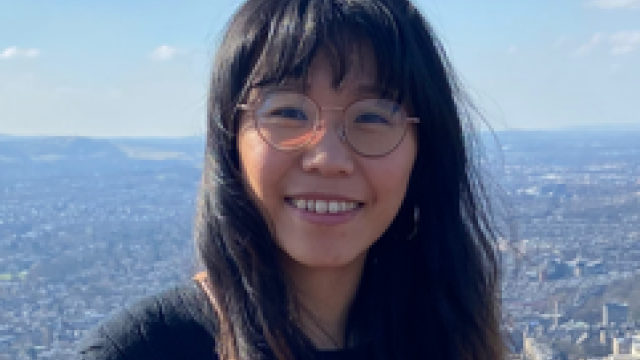 a woman wearing glasses with a view over acity